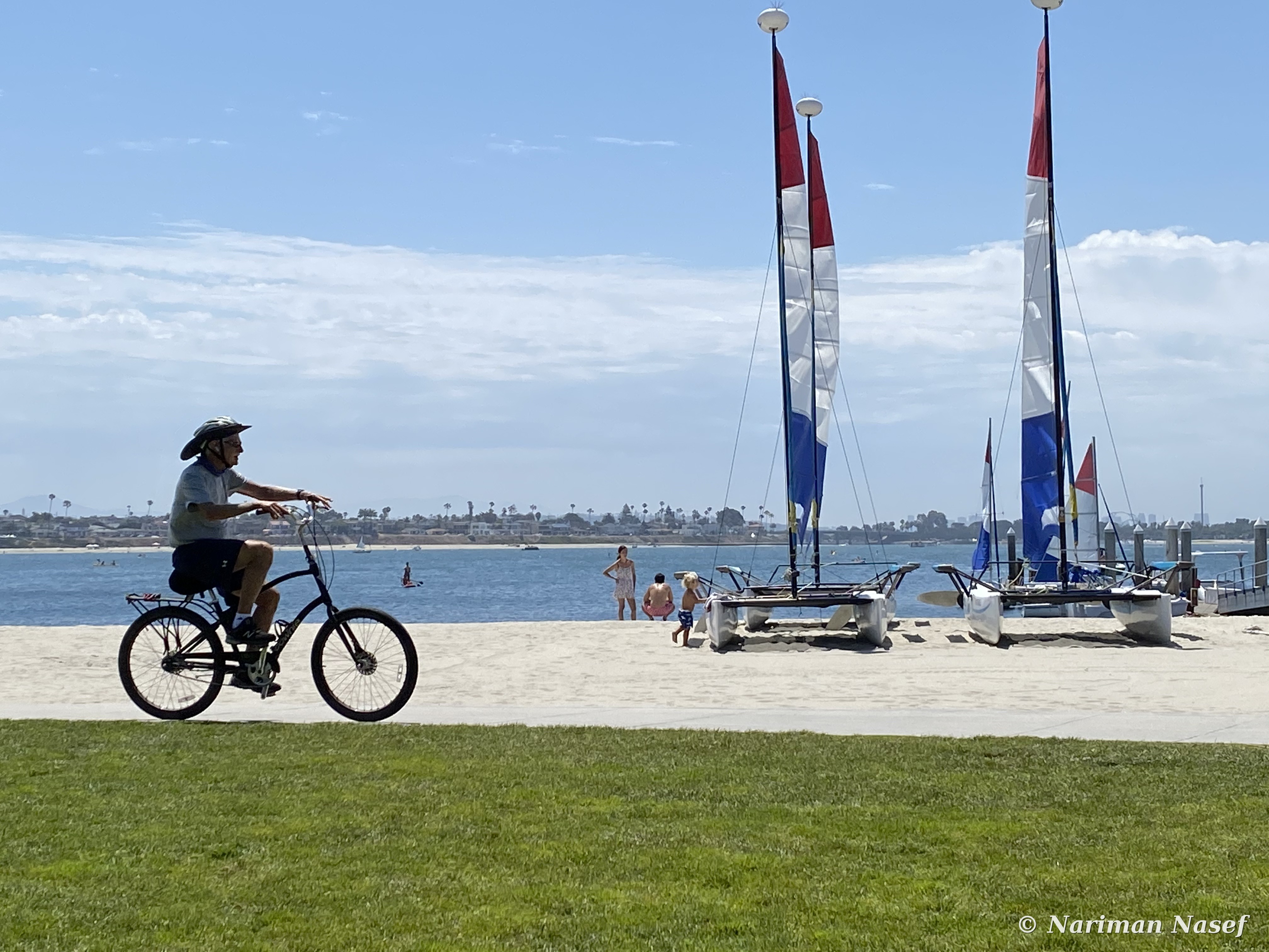 Cyclist riding past sailboats at Mission Bay